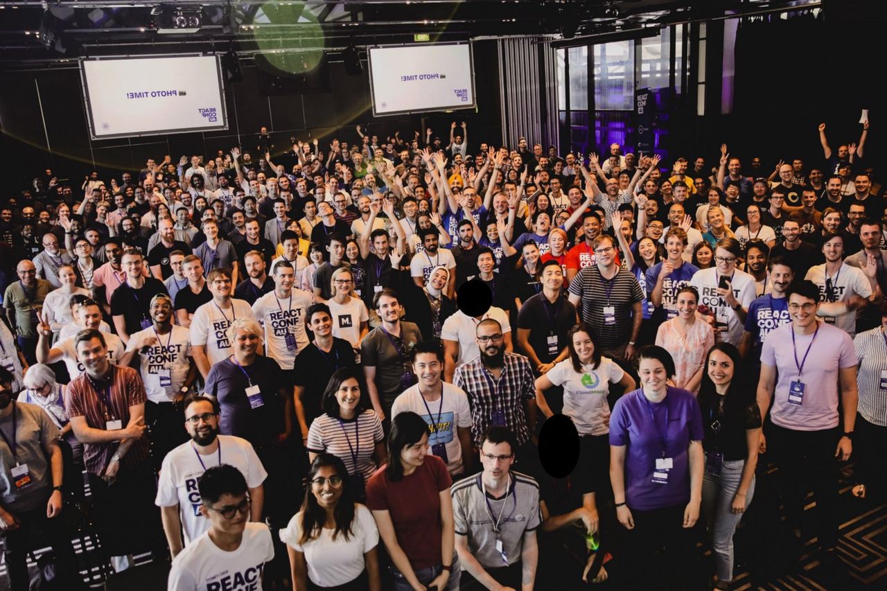 Overhead image of a happy crowd at ReactConf Au looking at the camera